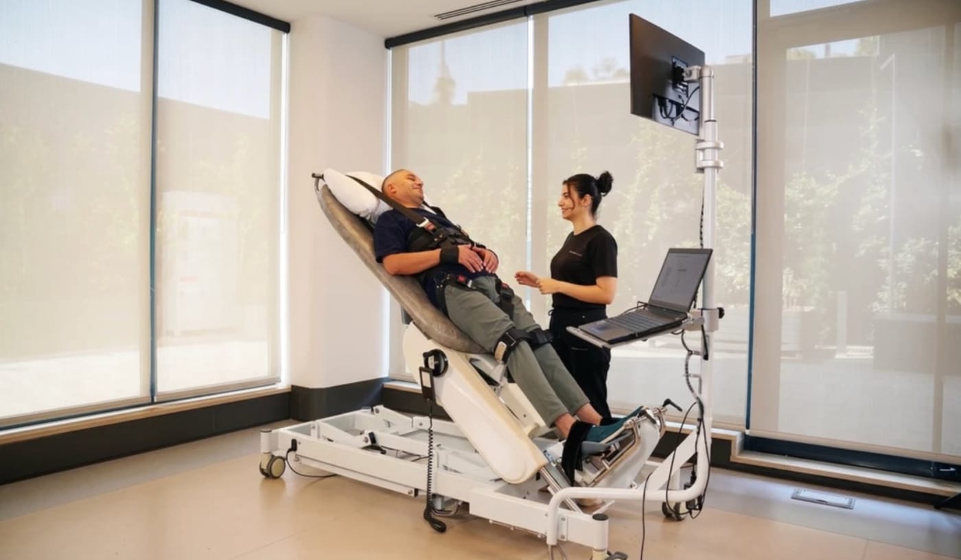 A patient on the Erigo robotic tilt table being brought upright by a therapist
