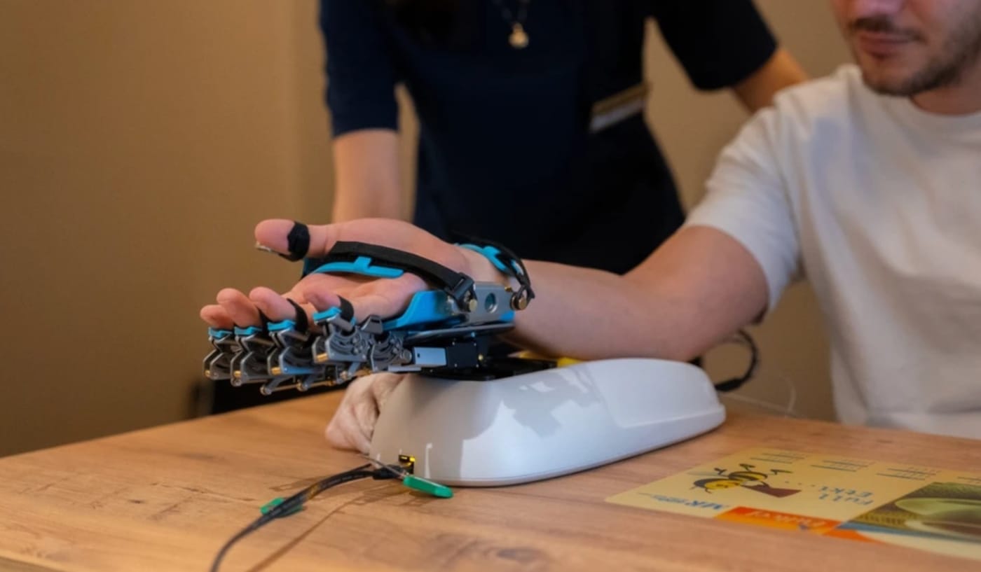 A patient’s hand strapped into a hand and finger rehabilitation robot