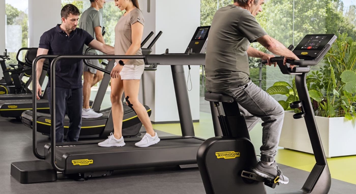 Patients exercising on Technogym treadmills and bikes with a physiotherapist