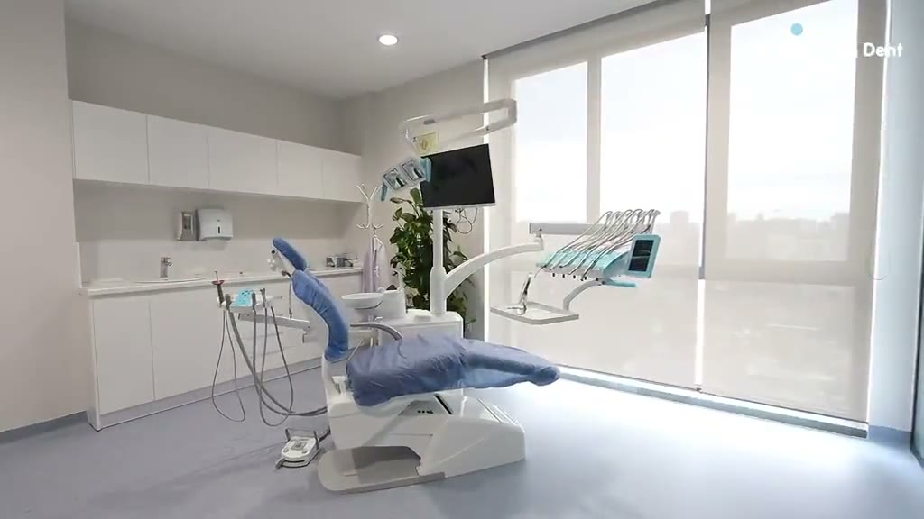 A dental treatment room at Trita Dent with a blue dental chair and large windows